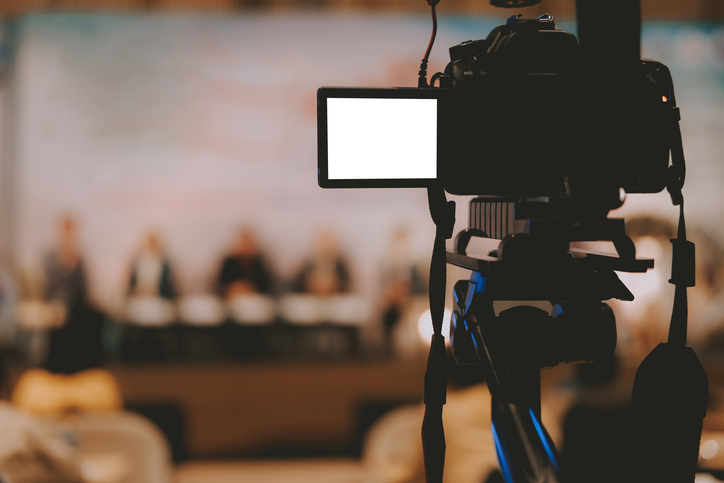 professional video production camera recording live event on stage. television social media broadcasting seminar conference.